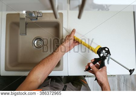 Worker Seals Kitchen Sink With Sealant. Hands Of Worker Works With Construction Sealant Gun In The K
