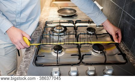 Male Hand Interior Designer Using Tape Measure On Gas Stove On Modern Countertop In Kitchen Showroom