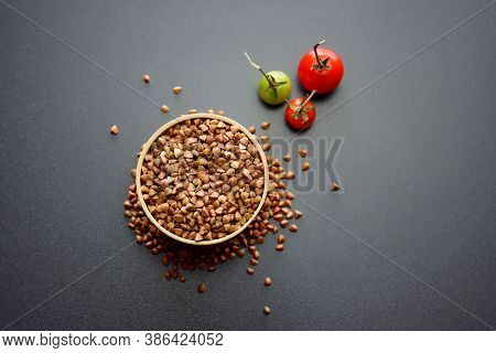 Buckwheat In A Round Wooden Bowl On A Gray Background.