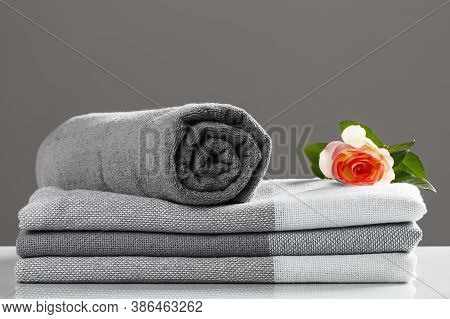 A Stack Of Folded Blanket And A Roll Of Towel. Monochrome Gray White Textile Set.