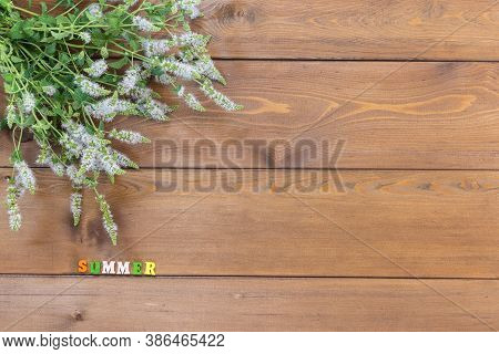 A Bouquet Of Blooming Oregano Lies On A Brown Wooden Table. Sunny Summer. Multicolored Letters. Copy