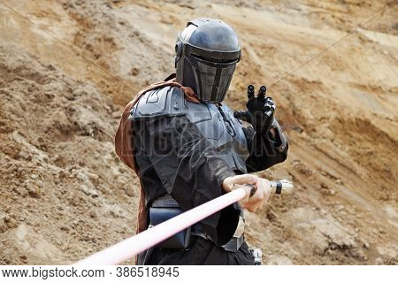 Umea, Norrland Sweden - August 14, 2020: Jedi Swings His Lightsaber In A Sand Pit