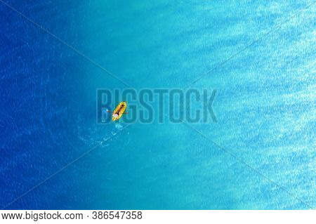 Yellow packraft rubber boat and turquoise water waves from top view. Active travel summer vacations seascape background from drone