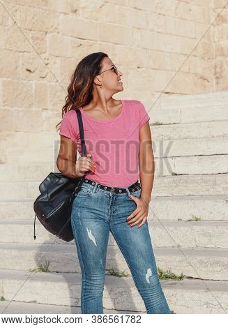 Young Women Wearing T-shirt And Jeans Going Down The  Stairs