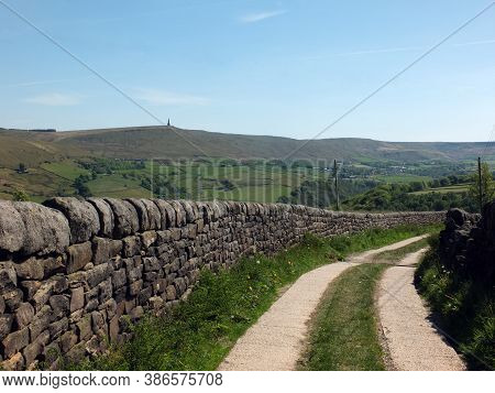 View Of A A Curved Narrow Country Road Surrounded By Stone Walls And Flowers In West Yorkshire Count