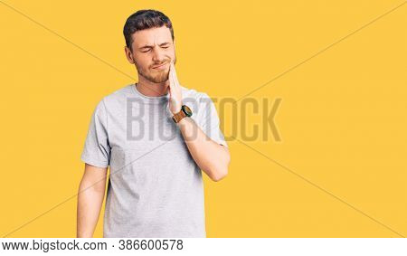 Handsome young man with bear wearing casual tshirt touching mouth with hand with painful expression because of toothache or dental illness on teeth. dentist 