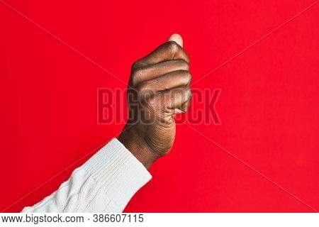 Arm and hand of african american black young man over red isolated background holding blank space with thumb finger, business and advertising 