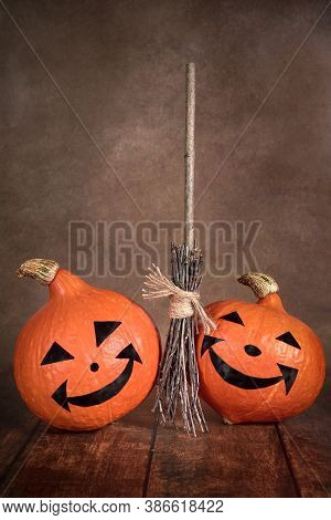 Two Halloween Pumpkins And A Witchs Broom On A Dark Background.