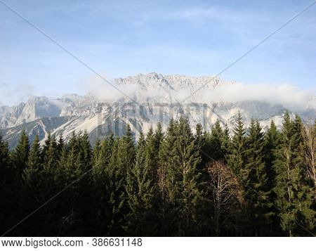 Landscape With Snowy Mountains In Fog And Forest Against A Blue Sky