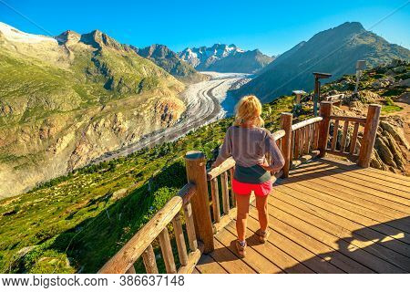 Tourist Woman From Viewing Platform Looking Alpine Glacier. Aletsch Glacier From Moosfluh Viewpoint 