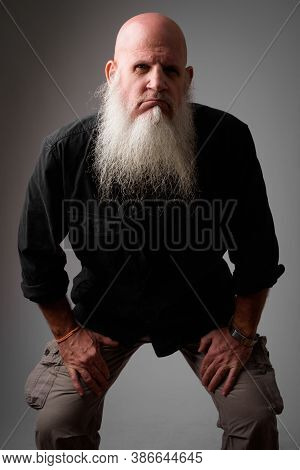 Stressed Mature Bald Man With Long Beard Looking Angry While Leaning Forward