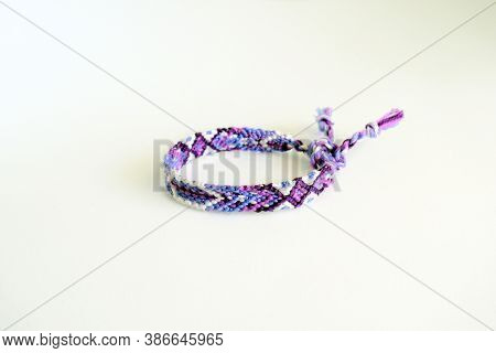 Selective Focus Of Tied Woven Friendship Bracelet With Bright Purple Pattern Handmade Of Thread Isol