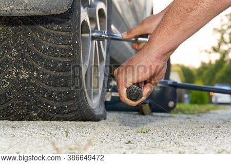 Man Changing Wheel. Tire Changer Changing Flat Car Tire. Help On Road Concept. Mechanic Hands Unscre