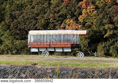 The Trailer On The Grassy Hill And Background Mountain Range. The Drawbar Trailer For Tourist Passen