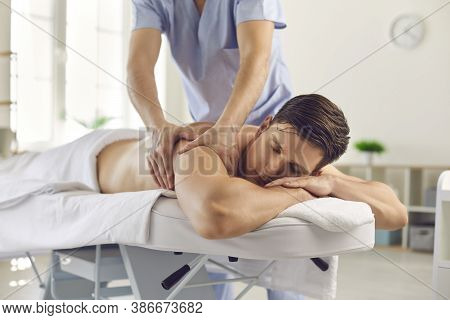 Relaxed Young Man Getting Back Massage Done By Professional Massagist Or Physiotherapist
