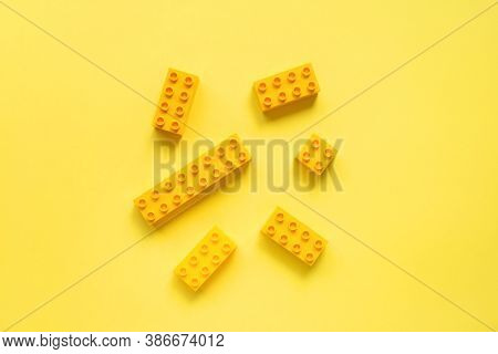 Childrens Building Blocks Similar To Legos, Yellow Blocks On Yellow Background. Monochrome Photo, To