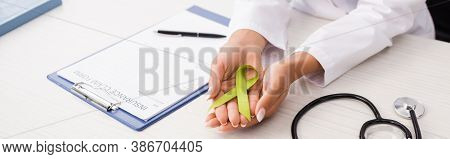 Cropped View Of Doctor Holding Green Awareness Ribbon Near Stethoscope And Insurance Claim Form, Men