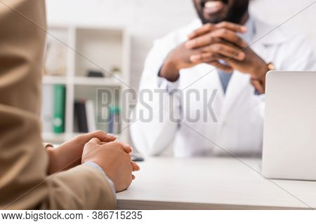 Cropped View Of African American Doctor Sitting With Clenched Hands Near Patient