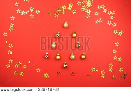 Christmas Tree Made Of Ball Decoration On Red Background With Golden Confetti Stars. Concept Holiday