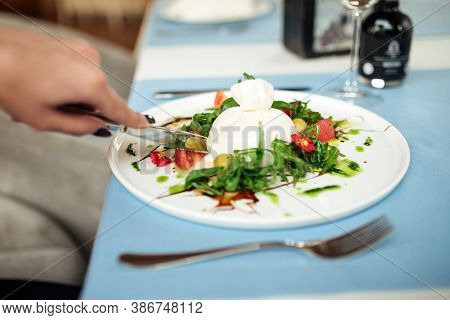 Eating Gourmet Spanish Buratta Salad With Vegetables And Greens