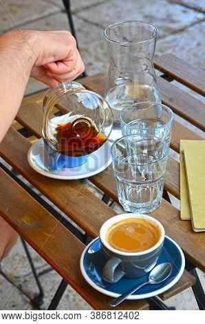 Man Hand Poring Filter Coffee And Espresso Lungo In Blue Cups With Pitcher Of Water On A Wooden Tabl