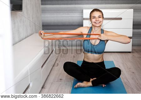 Woman At Home Trying To Lose Weight And Have Training With Elastic Band In Her Hands. She Looks At T