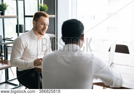 Handsome Red-haired Young Businessman Talking To African American Business Partner About New Project