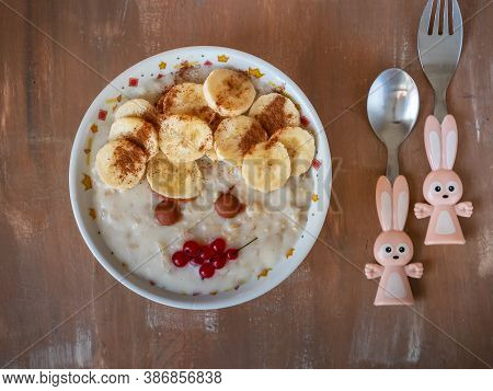 Breakfast For Toddler, Oatmeal Porridge With Bannans, Currants And Caramel In A Deep Plate