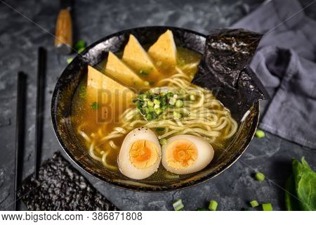 Homemade Vegetarian Japanese Ramen Noudle Soup With Fried Tofu Slices, Egg And Spring Onions In Dark