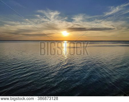 Beautiful Yellow Sunset On The Sea And Obloka On The Blue Sky, Reflected In The Sea Mirror.