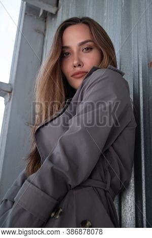 Gorgeous Asian Attractive Model Wearing Gray Trench Coat Standing Near Wall Shot From Lower Point. O