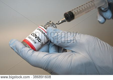 Doctor Holding A Syringe And A Vial With Covid-19 Virus Vaccine Isolated On Gray Background. Pharmac
