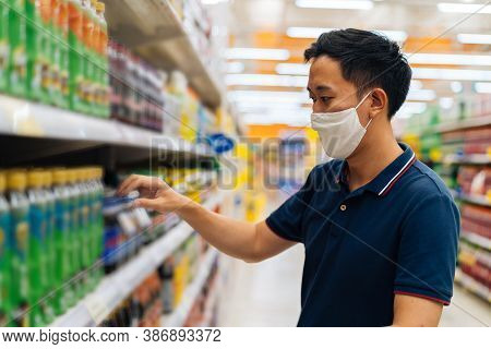 Young Adult Asian Man Wearing A Face Mask While Shopping With Cart Trolley In Grocery Supermarket St