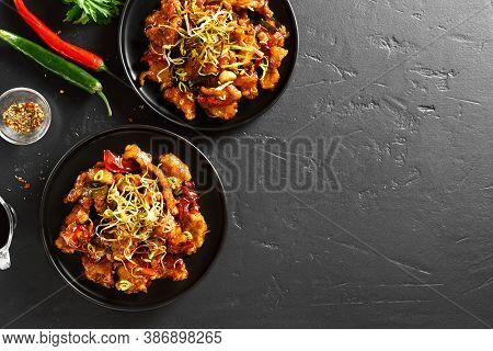 Spicy Garlic Fried Chicken (kkanpunggi). Asian Chicken In Sweet And Sour Sauce On Plate Over Black S