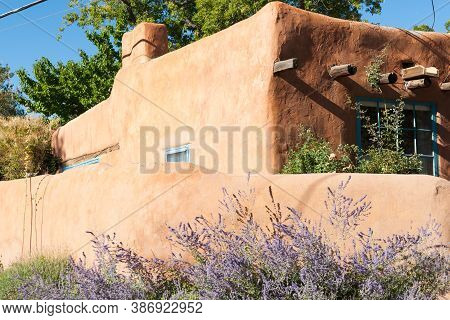 Exterior Wall And Purple Wildflowers Outside Boundary Wall In Pueblo Style Architecture