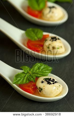 ชี Mozzerella น้ำมันมะกอก มะเขือเทศ และใบโหระพาเป็นจาน