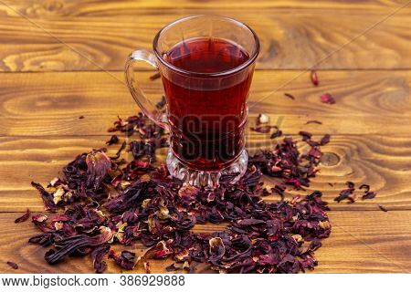 Glass Cup Of Red Hibiscus Tea (carcade, Roselle) On Wooden Table