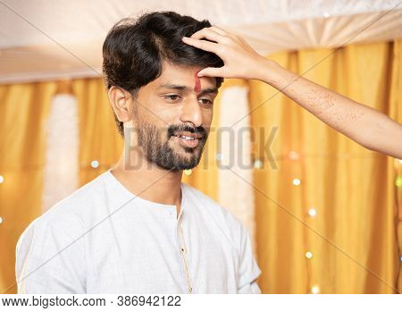 Close Up Hands Of Sister Applying Tilak Or Mark To Forehead Of Elder Brother During Bhai Dooj Or Bha