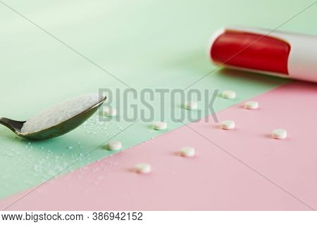 Sugar Substitute Tablets And Natural Sweetener Powder On A Green-pink Background.