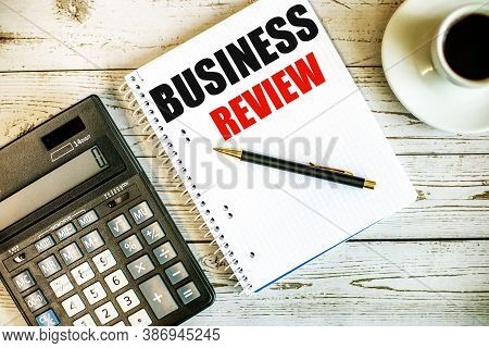 Business Review Written On White Paper Near Coffee And Calculator On A Light Wooden Table. Business 