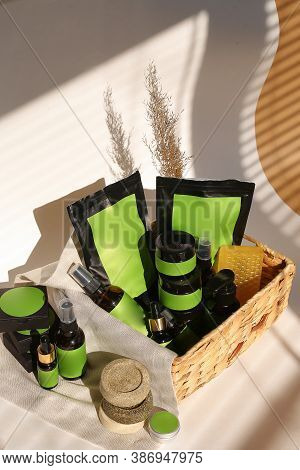 Cosmetic Bottles, Jars And Doy Packs In Wicker Basket With Green Space For Brand.