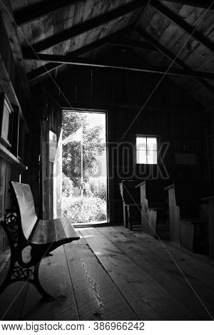 Light Streams Through The Doorway And Window Exposing Desks In A Rural One Room Schoolhouse. (black 