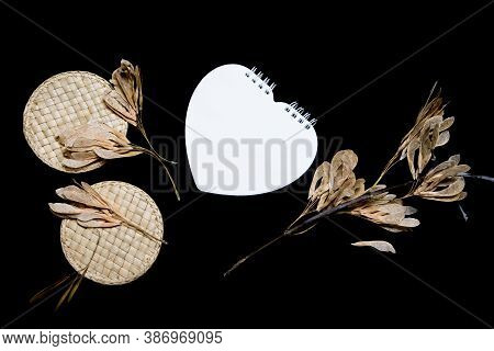 Mock-up Scene. Blank Heart-shaped Notebook, Dry Seeds And Straw Work Isolated On Black Background. B