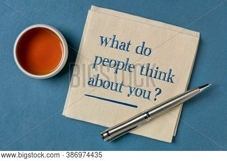 What do people think about you? Handwriting on a napkin with a cup of tea. Communication, self image and personal development concept.