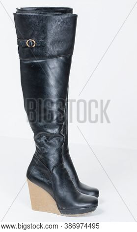 Stylish woman in black dress wearing overknee boots