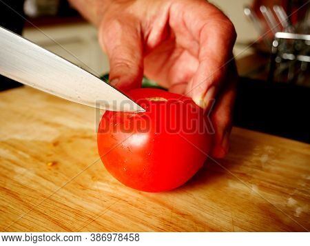 Man Cutting Tomatoes On A Wooden Board