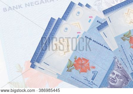 1 Malaysian Ringgit Bills Lies In Stack On Background Of Big Semi-transparent Banknote. Abstract Pre