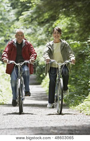 Longitud total de un hombre maduro y medio de edad a mujer de ciclismo en carretera de bosque