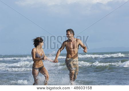 Wesoły semidressed para działa w surf Beach