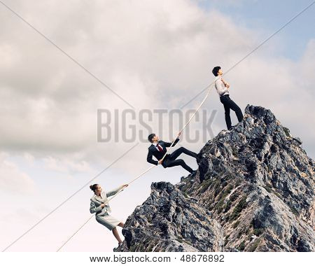 Imagem de três empresários puxando a corda no topo da montanha